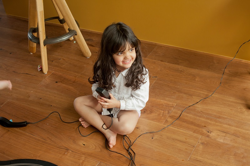 Menina sentada em um espaço revestido com piso laminado, para demonstrar que o piso laminado é resistente.