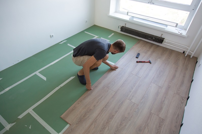 Homem instalando piso laminado, que é um dos melhores pisos para quem tem pets em casa.
