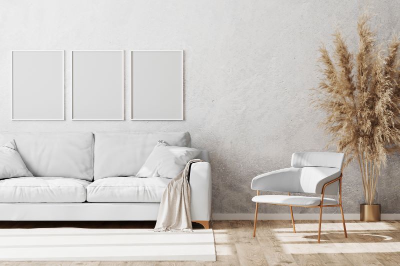 sala de estar no estilo escandinavo, com sofá e cadeira brancos, tapete em tom de areia, parede em cimento claro e piso vinílico em tom claro de madeira