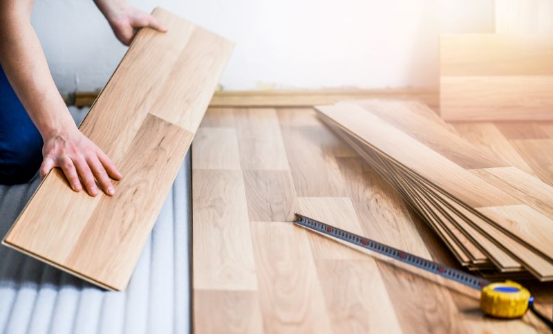 Como instalar piso laminado: mãos de trabalhador instalando piso laminado.