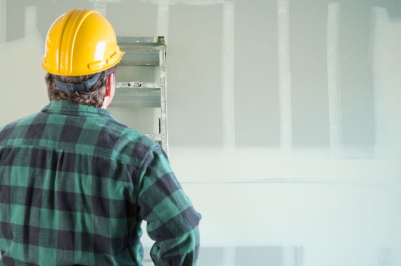 patologia em parede de drywall​: profissional observando parede de drywall